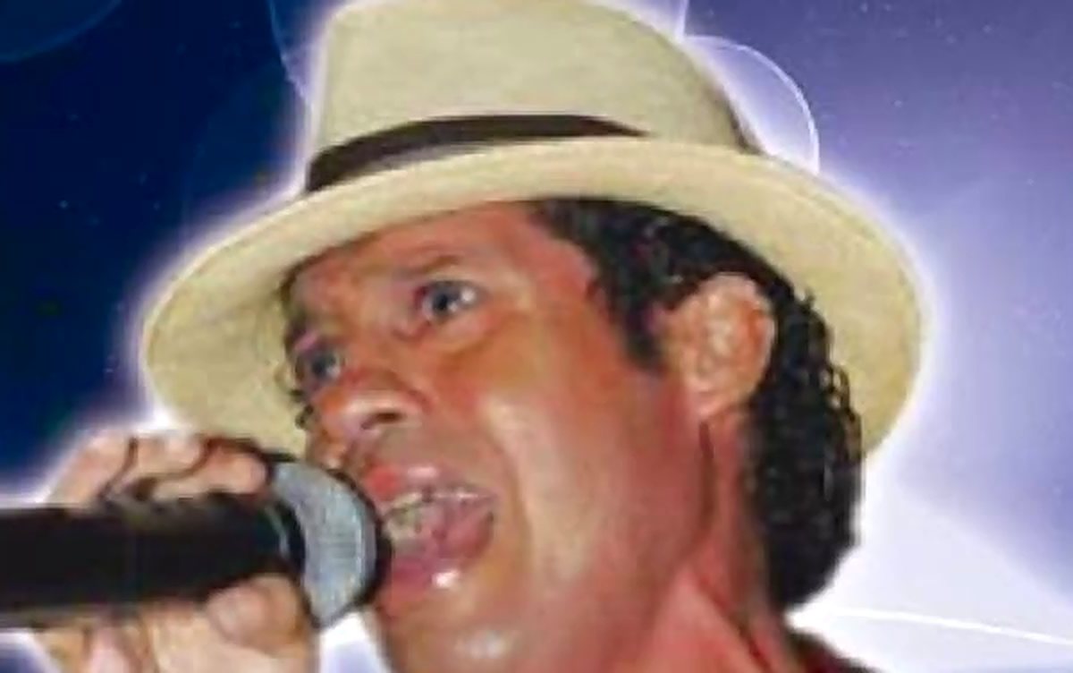 Fadhyd cantando con sombrero y micrófono en una presentación